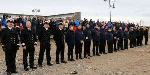 Members of the Coastal Rescue Services standing to attention at the shoreline.